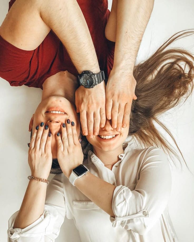 Two friends covering each other's eyes, laughing